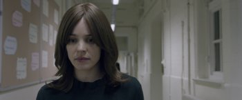 Movie still from “Disobedience” (2017), directed by Sebastián Lelio – A woman standing in a hallway looking at the camera; Close Up shot, Over the shoulder angle