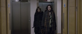 Movie still from “Disobedience” (2017), directed by Sebastián Lelio – Two women walking in an elevator in a building; Medium shot, Over the shoulder angle