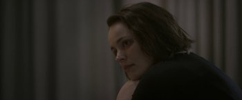 Movie still from “Disobedience” (2017), directed by Sebastián Lelio – A person sitting down with her eyes closed; Close Up shot, Over the shoulder angle