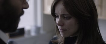 Movie still from “Disobedience” (2017), directed by Sebastián Lelio – A person looking down at something; Close Up shot, Over the shoulder angle