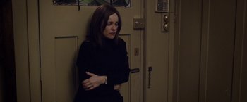 Movie still from “Disobedience” (2017), directed by Sebastián Lelio – A woman leaning against a door with her arms crossed; Medium shot, Over the shoulder angle