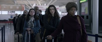 Movie still from “Disobedience” (2017), directed by Sebastián Lelio – A group of people waiting to board an airplane; Medium shot, Over the shoulder angle