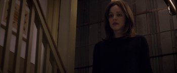 Movie still from “Disobedience” (2017), directed by Sebastián Lelio – A woman in a black shirt standing next to a staircase; Medium shot, Over the shoulder angle