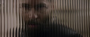 Movie still from “Disobedience” (2017), directed by Sebastián Lelio – A man with a beard and glasses looking out a window; Extreme Close Up shot, Low angle