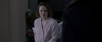 Movie still from “Disobedience” (2017), directed by Sebastián Lelio – A woman in a pink shirt is sitting in a room; Medium shot, Over the shoulder angle