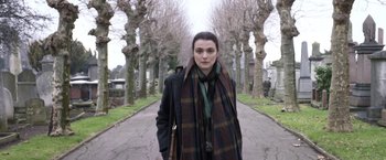 Movie still from “Disobedience” (2017), directed by Sebastián Lelio – A woman wearing a scarf standing on a sidewalk; Medium shot, High angle