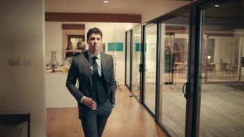 Movie still from “Black Mirror” (2011), created by Charlie Brooker – A man in a suit standing in front of a window; Medium shot, Low angle
