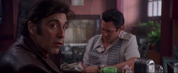Movie still from “Donnie Brasco” (1997), directed by Mike Newell – Two men are sitting at a table and one of them is looking at the camera; Close Up shot, Over the shoulder angle