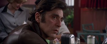Movie still from “Donnie Brasco” (1997), directed by Mike Newell – A person sitting at a table; Close Up shot, Over the shoulder angle