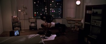 Movie still from “Donnie Brasco” (1997), directed by Mike Newell – A man is lifting a barbell in a living room; Wide shot, High angle