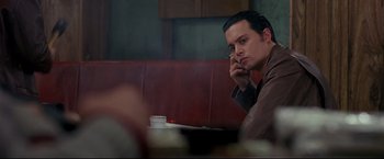 Movie still from “Donnie Brasco” (1997), directed by Mike Newell – A man sitting in a booth at a restaurant with a cigarette in his mouth; Close Up shot, Over the shoulder angle