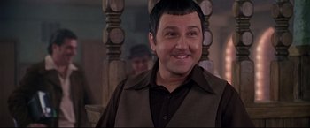 Movie still from “Donnie Brasco” (1997), directed by Mike Newell – A man in a brown shirt and a brown vest smiling; Close Up shot, Over the shoulder angle