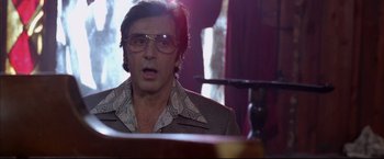 Movie still from “Donnie Brasco” (1997), directed by Mike Newell – A man with glasses is sitting at a desk; Close Up shot, Low angle