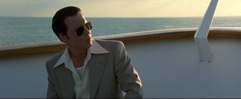 Movie still from “Donnie Brasco” (1997), directed by Mike Newell – A man wearing a suit and sunglasses on a boat; Close Up shot, Low angle