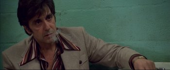 Movie still from “Donnie Brasco” (1997), directed by Mike Newell – A man in a suit smoking a cigarette in front of a green wall; Close Up shot, Low angle
