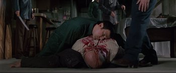 Movie still from “Donnie Brasco” (1997), directed by Mike Newell – A man laying on the ground with blood all over his face; Medium shot, High angle