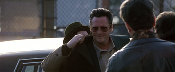 Movie still from “Donnie Brasco” (1997), directed by Mike Newell – A person wearing a hat and sunglasses; Close Up shot, Over the shoulder angle