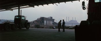 Movie still from “Donnie Brasco” (1997), directed by Mike Newell – Two men standing in front of an industrial building; Extreme Wide shot, Over the shoulder angle