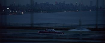 Movie still from “Donnie Brasco” (1997), directed by Mike Newell – A car driving down a street next to a body of water at night; Extreme Wide shot, High angle
