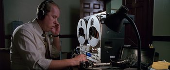 Movie still from “Donnie Brasco” (1997), directed by Mike Newell – A man is looking at a reel to reel tape recorder; Medium shot, Low angle