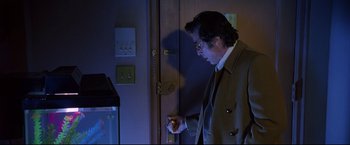 Movie still from “Donnie Brasco” (1997), directed by Mike Newell – A man in a brown jacket is looking at a door; Medium shot, Low angle
