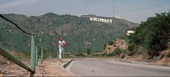 Movie still from “Earthquake” (1974), directed by Mark Robson – A man walking down a street in front of a hollywood sign; Extreme Wide shot, Low angle