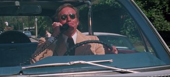 Movie still from “Earthquake” (1974), directed by Mark Robson – A man sitting in the drivers seat of a car talking on the phone; Medium shot, Low angle