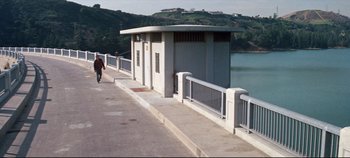 Movie still from “Earthquake” (1974), directed by Mark Robson – A person walking on a bridge near a body of water; Extreme Wide shot, High angle
