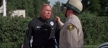 Movie still from “Earthquake” (1974), directed by Mark Robson – A police officer and another officer in a police uniform; Medium shot, Over the shoulder angle