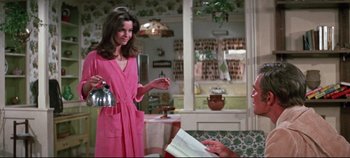 Movie still from “Earthquake” (1974), directed by Mark Robson – A woman in a pink robe holding a tea pot; Medium shot, Over the shoulder angle
