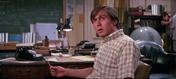 Movie still from “Earthquake” (1974), directed by Mark Robson – A man sitting at a desk holding a yellow pencil; Medium shot, High angle