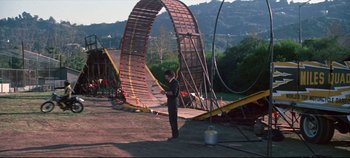 Movie still from “Earthquake” (1974), directed by Mark Robson – A man standing in front of an amusement park ride; Extreme Wide shot, Low angle