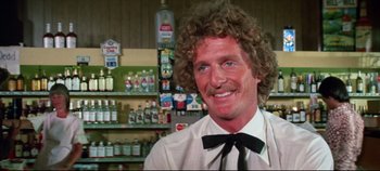 Movie still from “Earthquake” (1974), directed by Mark Robson – A man with curly hair wearing a white shirt and a black tie; Close Up shot, Over the shoulder angle