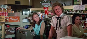 Movie still from “Earthquake” (1974), directed by Mark Robson – A man and a woman are standing at a counter; Medium shot, Over the shoulder angle