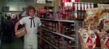 Movie still from “Earthquake” (1974), directed by Mark Robson – A man standing in front of shelves of canned goods; Medium shot, Low angle