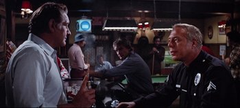 Movie still from “Earthquake” (1974), directed by Mark Robson – A group of people sitting around a bar; Medium shot, Over the shoulder angle
