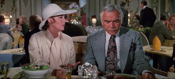 Movie still from “Earthquake” (1974), directed by Mark Robson – A man and a woman sitting at a dinner table; Medium shot, Over the shoulder angle