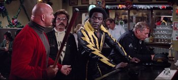 Movie still from “Earthquake” (1974), directed by Mark Robson – A group of people standing around a bar; Medium shot, Over the shoulder angle