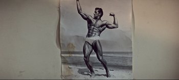 Movie still from “Earthquake” (1974), directed by Mark Robson – An old photo of a man posing on the beach; Medium shot, Low angle