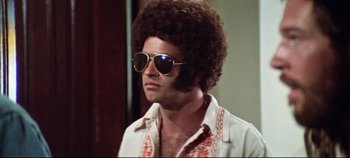 Movie still from “Earthquake” (1974), directed by Mark Robson – A man in a white shirt with sunglasses and a afro haircut; Close Up shot, Low angle