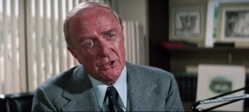 Movie still from “Earthquake” (1974), directed by Mark Robson – An older man wearing a suit and tie; Close Up shot, Over the shoulder angle
