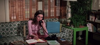 Movie still from “Earthquake” (1974), directed by Mark Robson – A woman sitting on a couch talking on the phone; Medium shot, High angle