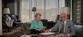 Movie still from “Earthquake” (1974), directed by Mark Robson – A woman sitting at a table with a man in a green jacket; Medium shot, Over the shoulder angle
