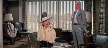 Movie still from “Earthquake” (1974), directed by Mark Robson – A woman wearing a hat sitting at a table; Medium shot, Over the shoulder angle