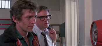 Movie still from “Earthquake” (1974), directed by Mark Robson – A couple of men standing next to each other; Close Up shot, Over the shoulder angle