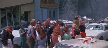 Movie still from “Earthquake” (1974), directed by Mark Robson – A group of people gathered around a police officer; Wide shot, Over the shoulder angle