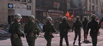 Movie still from “Earthquake” (1974), directed by Mark Robson – A group of men in military uniforms standing in front of a building; Wide shot, Low angle