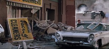 Movie still from “Earthquake” (1974), directed by Mark Robson – A car parked in front of a building that has been destroyed; Wide shot, Low angle
