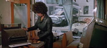 Movie still from “Earthquake” (1974), directed by Mark Robson – A woman standing in front of a table with food; Medium shot, Over the shoulder angle