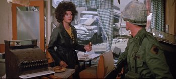 Movie still from “Earthquake” (1974), directed by Mark Robson – A woman holding a knife standing in front of a table; Medium shot, Over the shoulder angle